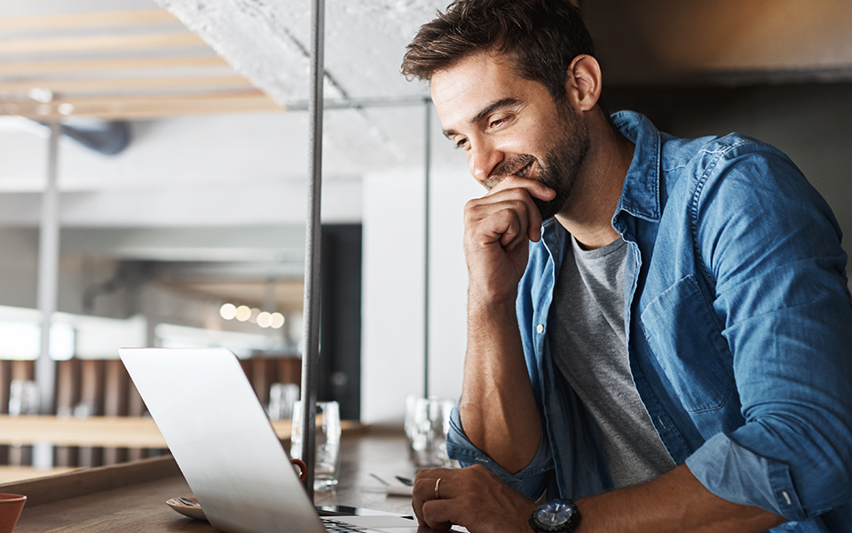 Investment-Services-960x600 – Capital Bank A man is looking at his laptop screen and smiling