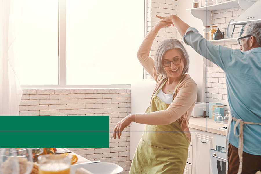 Photo of a man and woman dancing in the kitchen. He is holding her hand and twirling her
