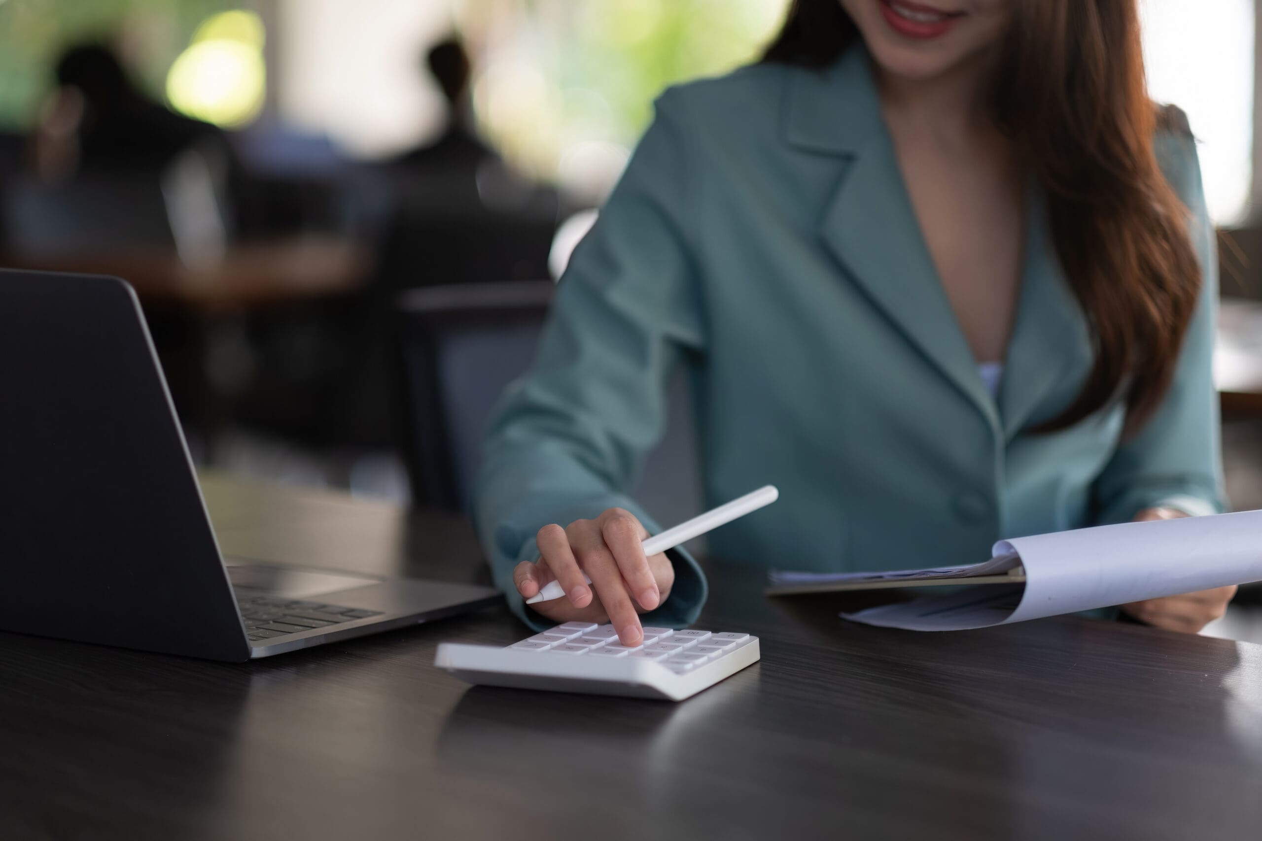 Woman using a calculator while holding a pen and paper.