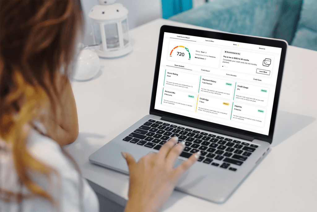 Person using a laptop to view a credit score dashboard with charts and cards on the screen, including a gauge showing 720.