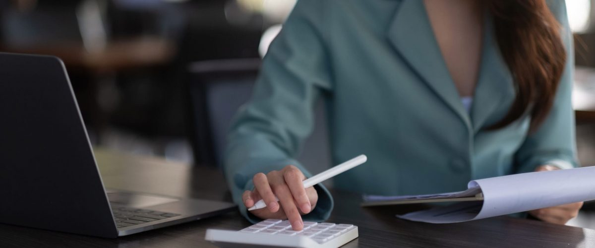 Woman using a calculator while holding a pen and paper.