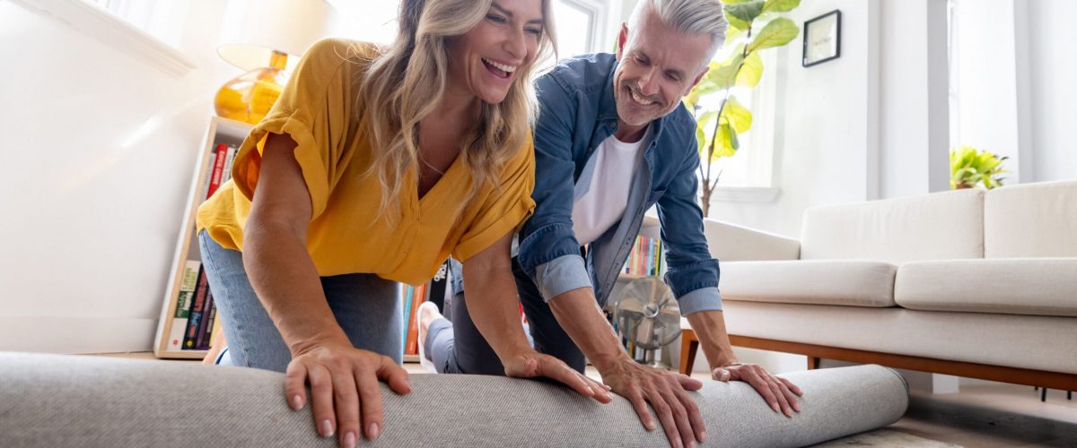 Photo of a couple unrolling a rug in their living room